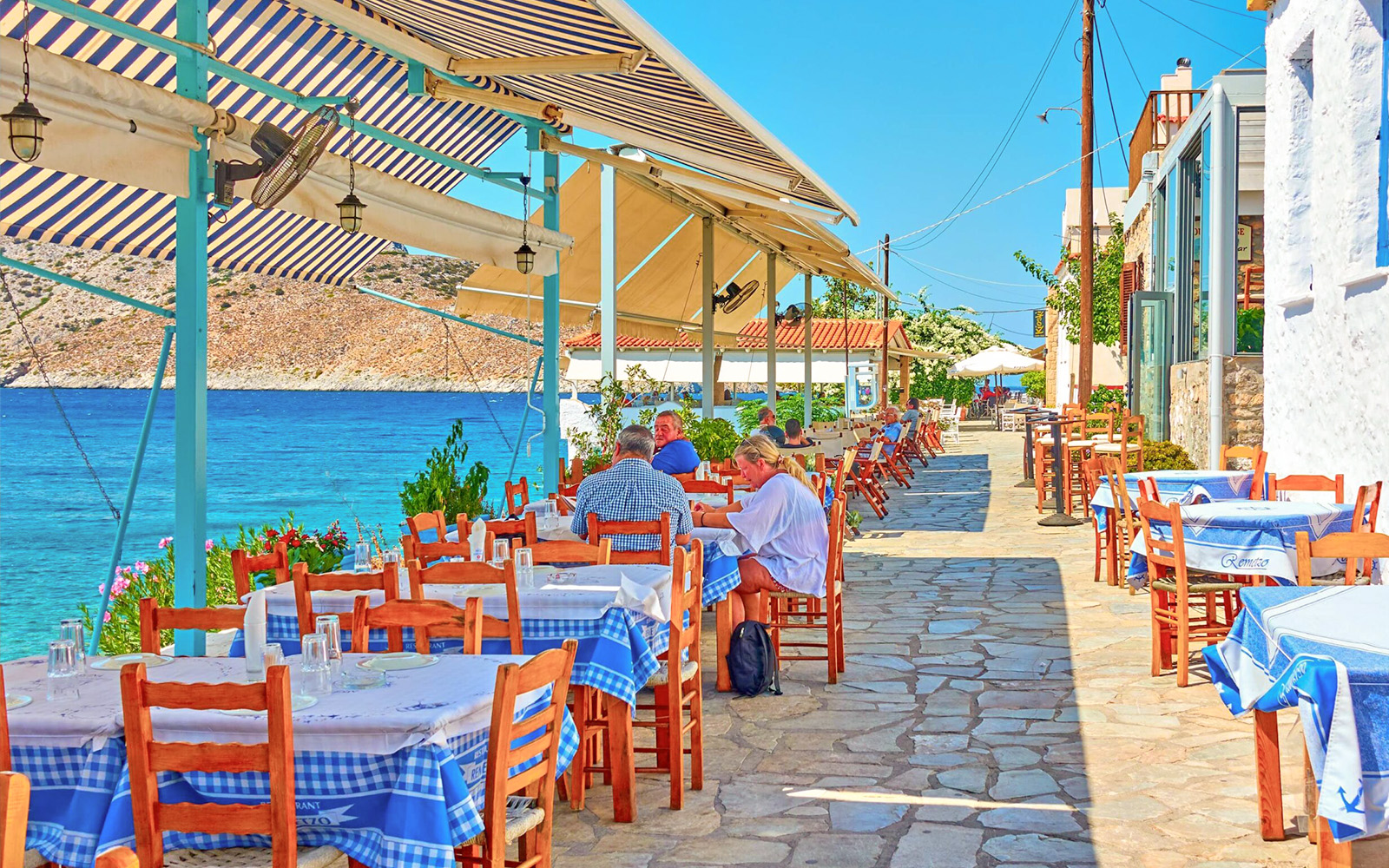 Outdoor seaside restaurant with blue tablecloths on Agistri island, Greece, part of Metopi, Agistri & Aegina cruise.