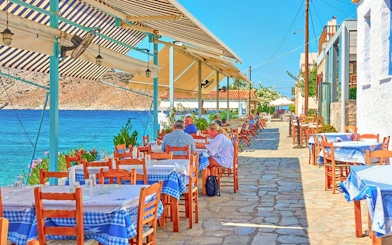 Outdoor seaside restaurant with blue tablecloths on Agistri island, Greece, part of Metopi, Agistri & Aegina cruise.