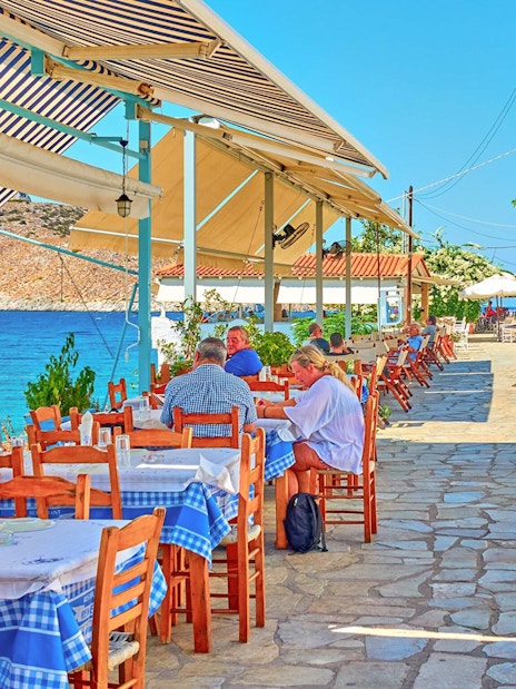 Outdoor seaside restaurant with blue tablecloths on Agistri island, Greece, part of Metopi, Agistri & Aegina cruise.