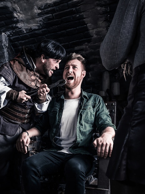 Visitors in a torture chamber scene at The Amsterdam Dungeon.