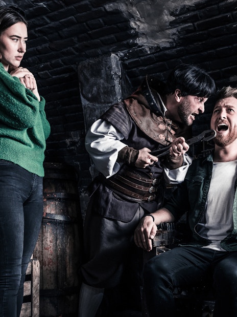 Visitors in a torture chamber scene at The Amsterdam Dungeon.