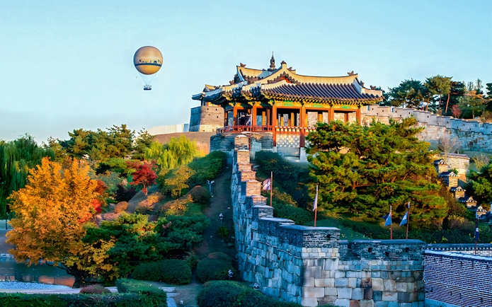 Hot air balloon over Suwon Hwaseong Fortress with autumn trees, part of Korean Folk Village tour.