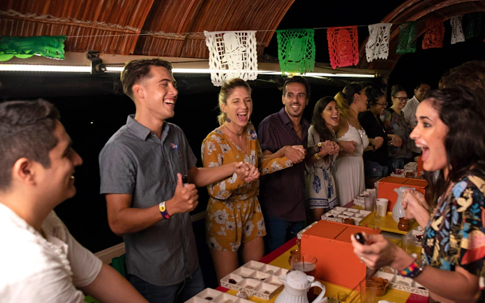 Guests enjoying a lively evening at Xoximilco Park with traditional decorations.