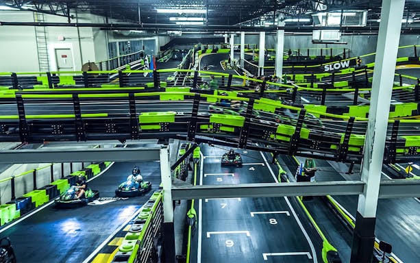 Indoor go-kart track at Andretti Indoor Karting, Orlando, with racers navigating the course.