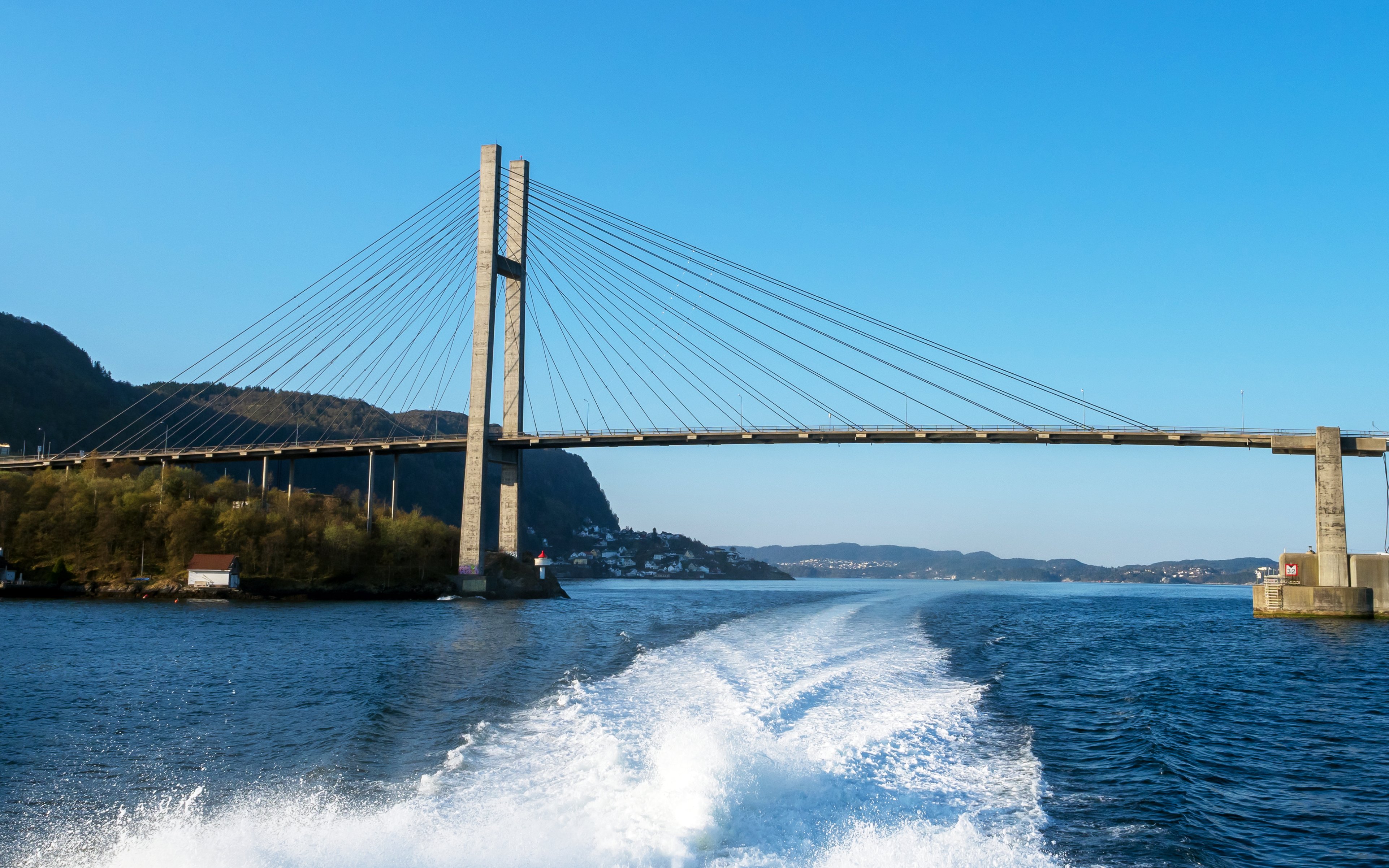 Boat cruising with Nordhordland Bridge in the background, Norway.