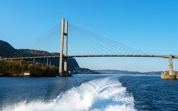 Boat cruising with Nordhordland Bridge in the background, Norway.