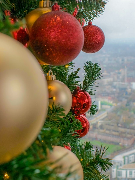 Christmas ornaments on a tree with a view of London from the Shard.