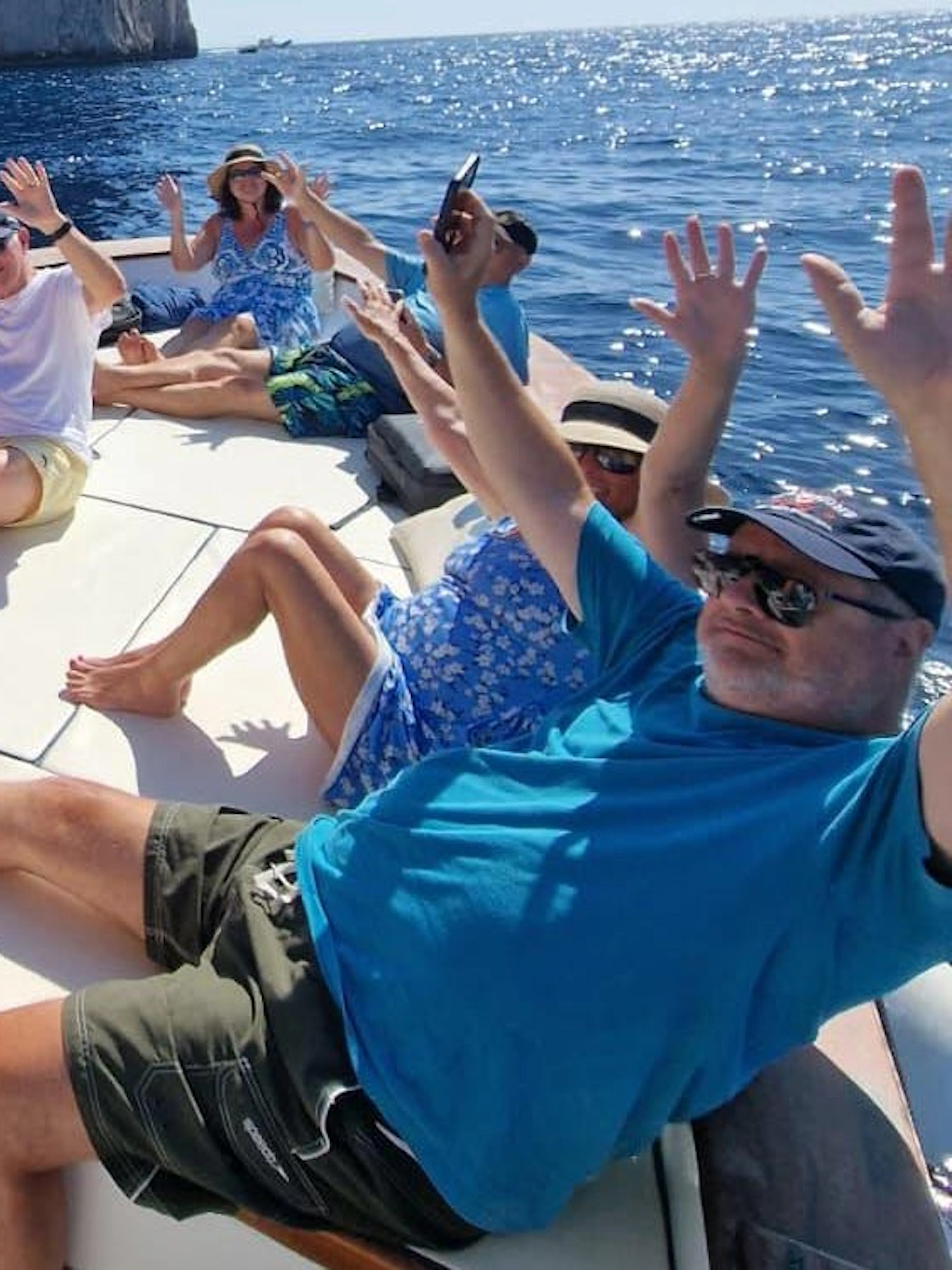 Tourists relaxing on a boat near Capri's Faraglioni rocks during a swimming stop.