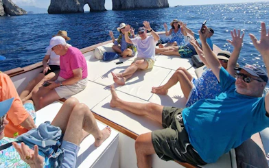 Tourists relaxing on a boat near Capri's Faraglioni rocks during a swimming stop.