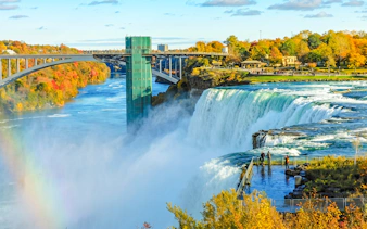 Niagara Falls with observation deck, rainbow, and surrounding autumn foliage during walking tour.