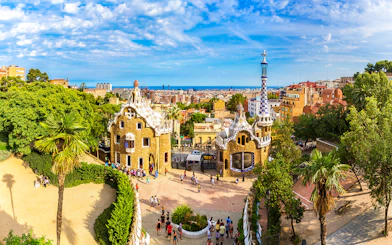 Tourists at Park Güell in Barcelona, Spain, exploring unique architecture with city views.