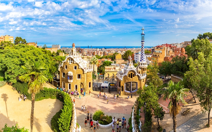 Tourists at Park Güell in Barcelona, Spain, exploring unique architecture with city views.