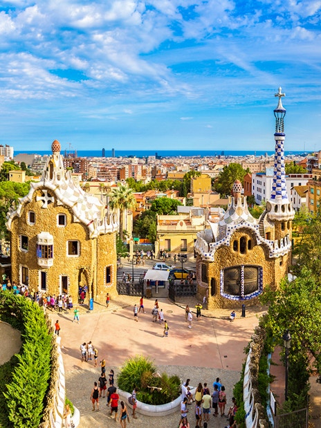 Tourists at Park Güell in Barcelona, Spain, exploring unique architecture with city views.