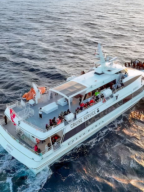 Motor catamaran on whale watching tour from Tromso, Norway, with passengers on deck.