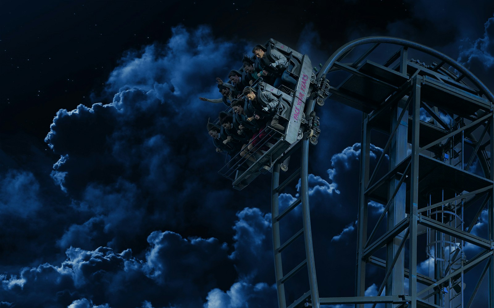 Roller coaster at night during Halloween in Thorpe Park with riders on a steep drop.