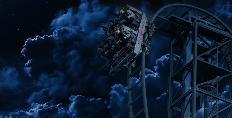 Roller coaster at night during Halloween in Thorpe Park with riders on a steep drop.