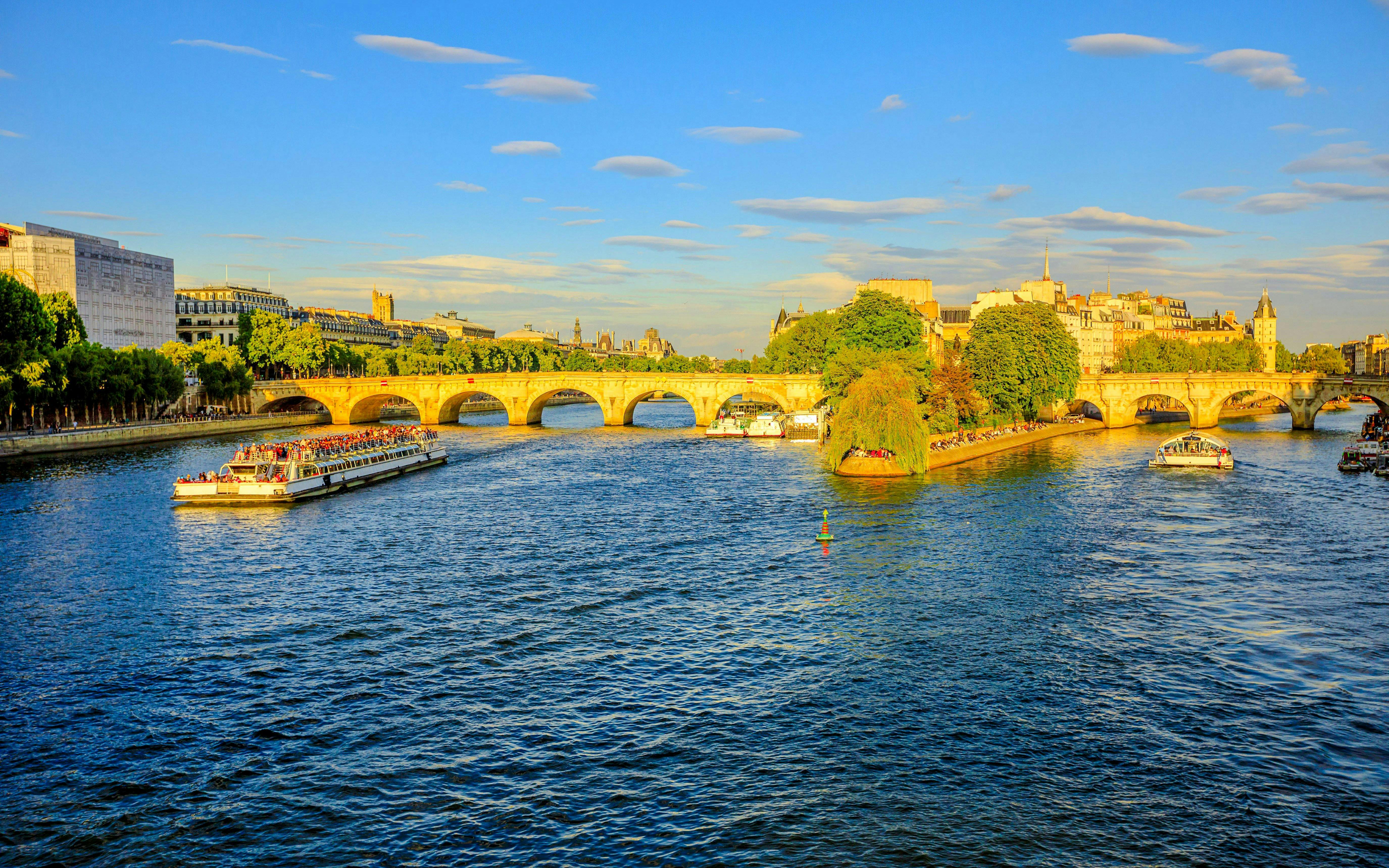 Seine River cruise boats passing under Pont Neuf in Paris.