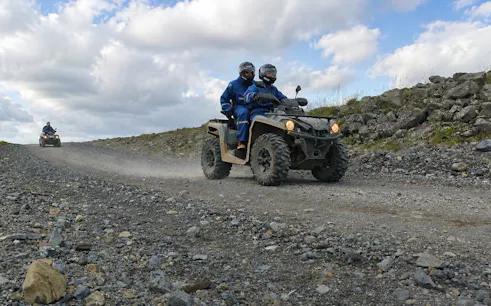 ATV riders on rocky trail during Reykjavik Peak tour with city and lake views.