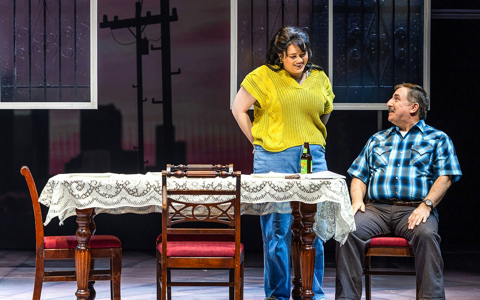 Scene from Real Women Have Curves: The Musical with two actors at a table.
