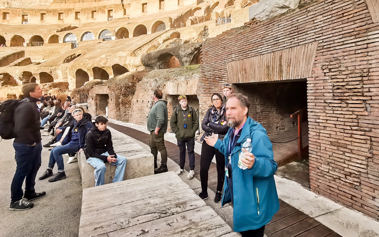 Tour group listening to a guide inside the Roman Colosseum, Rome.