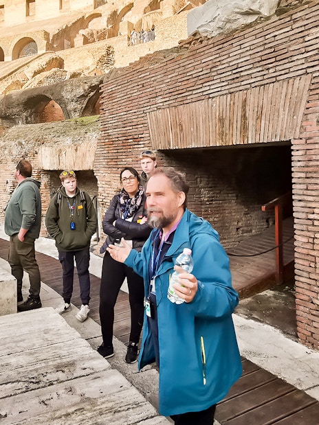 Tour group listening to a guide inside the Roman Colosseum, Rome.