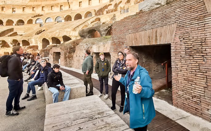 Tour group listening to a guide inside the Roman Colosseum, Rome.