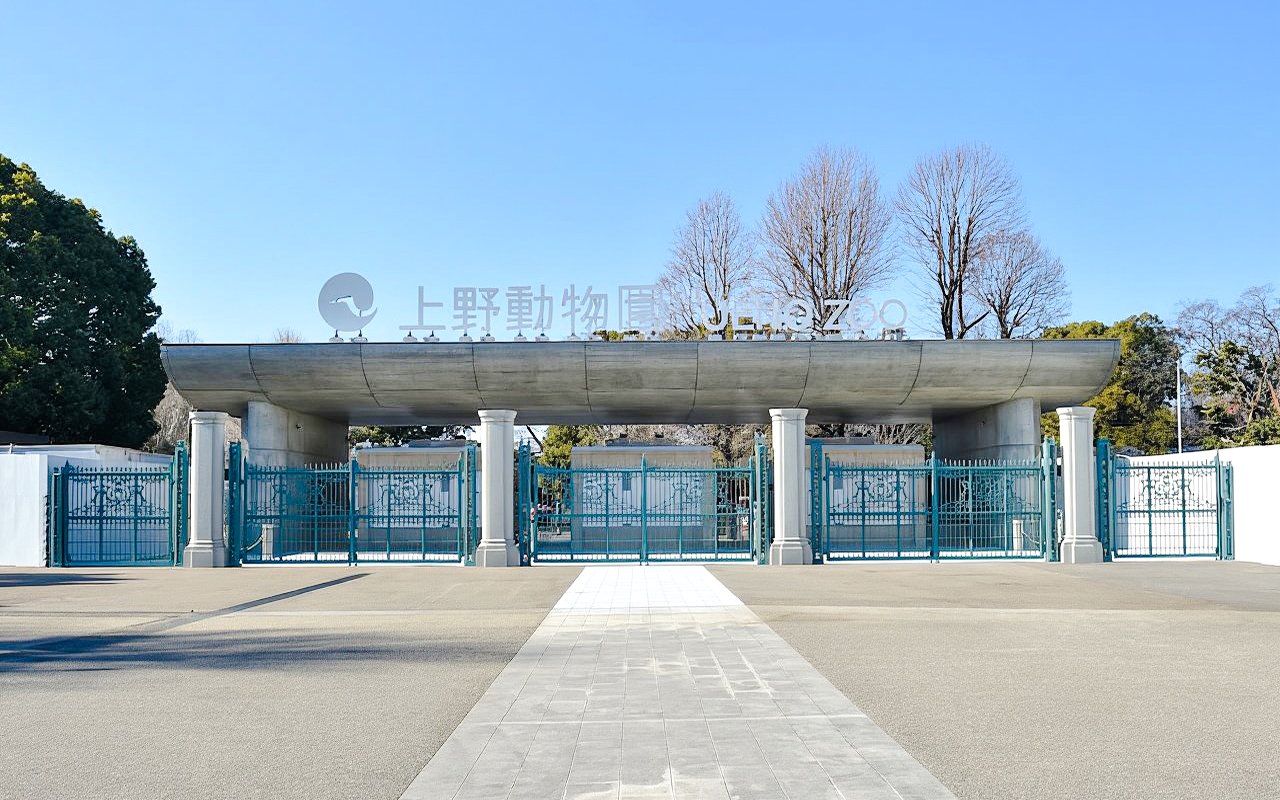 Main entrance gate to Ueno Zoo in Tokyo with blue gates and signage.