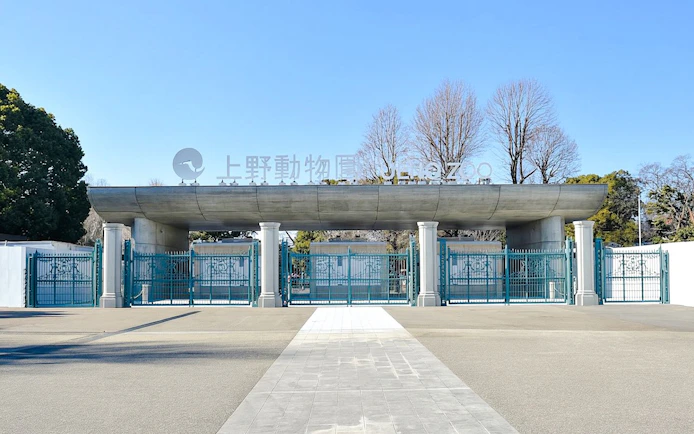 Main entrance gate to Ueno Zoo in Tokyo with blue gates and signage.