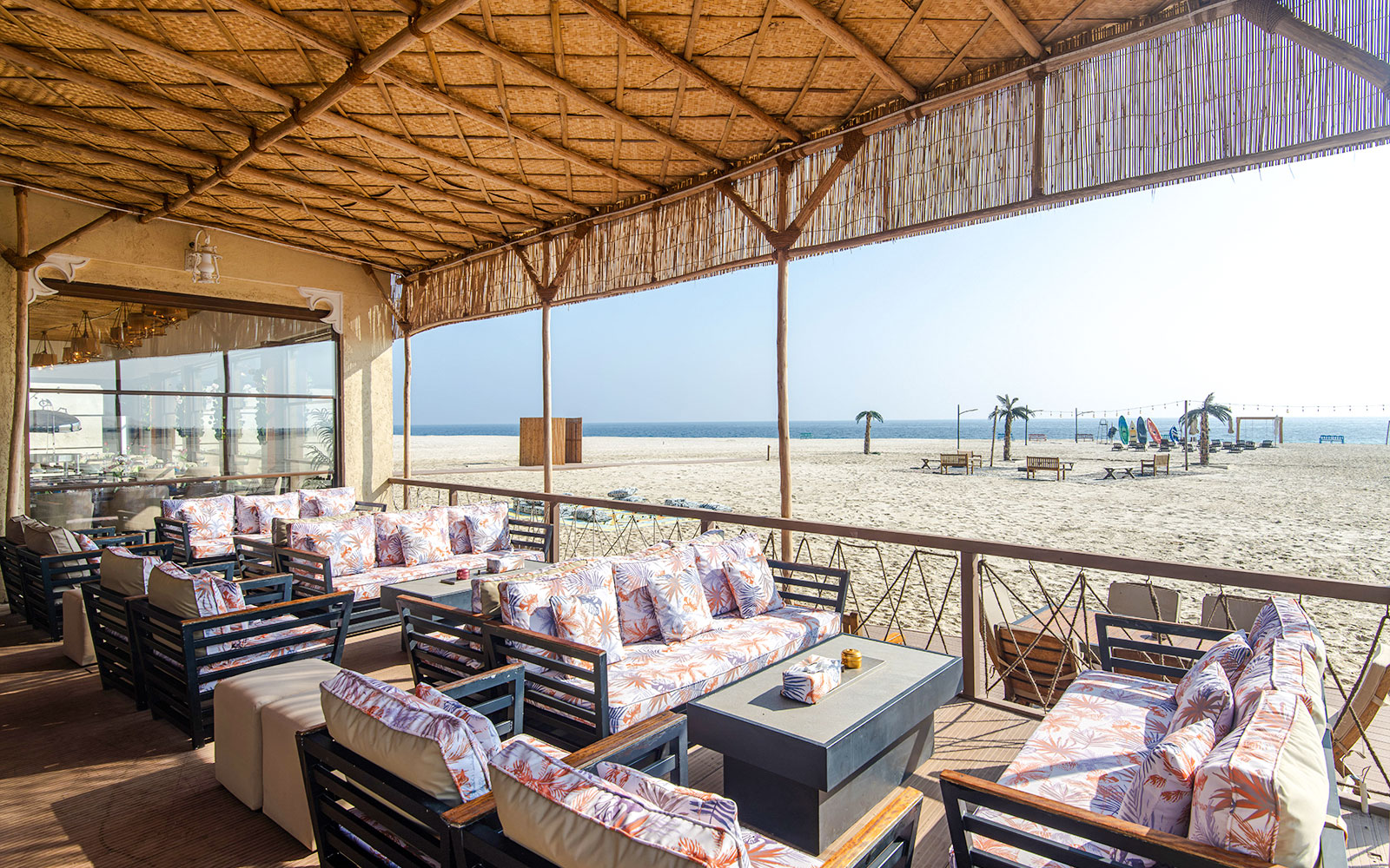 Outdoor seating area at Al Majles Resort overlooking sandy beach and ocean.