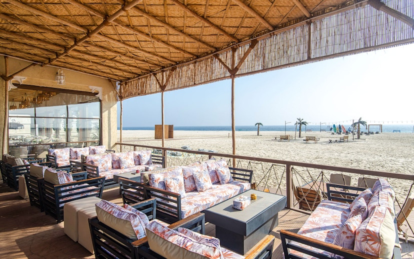 Outdoor seating area at Al Majles Resort overlooking sandy beach and ocean.