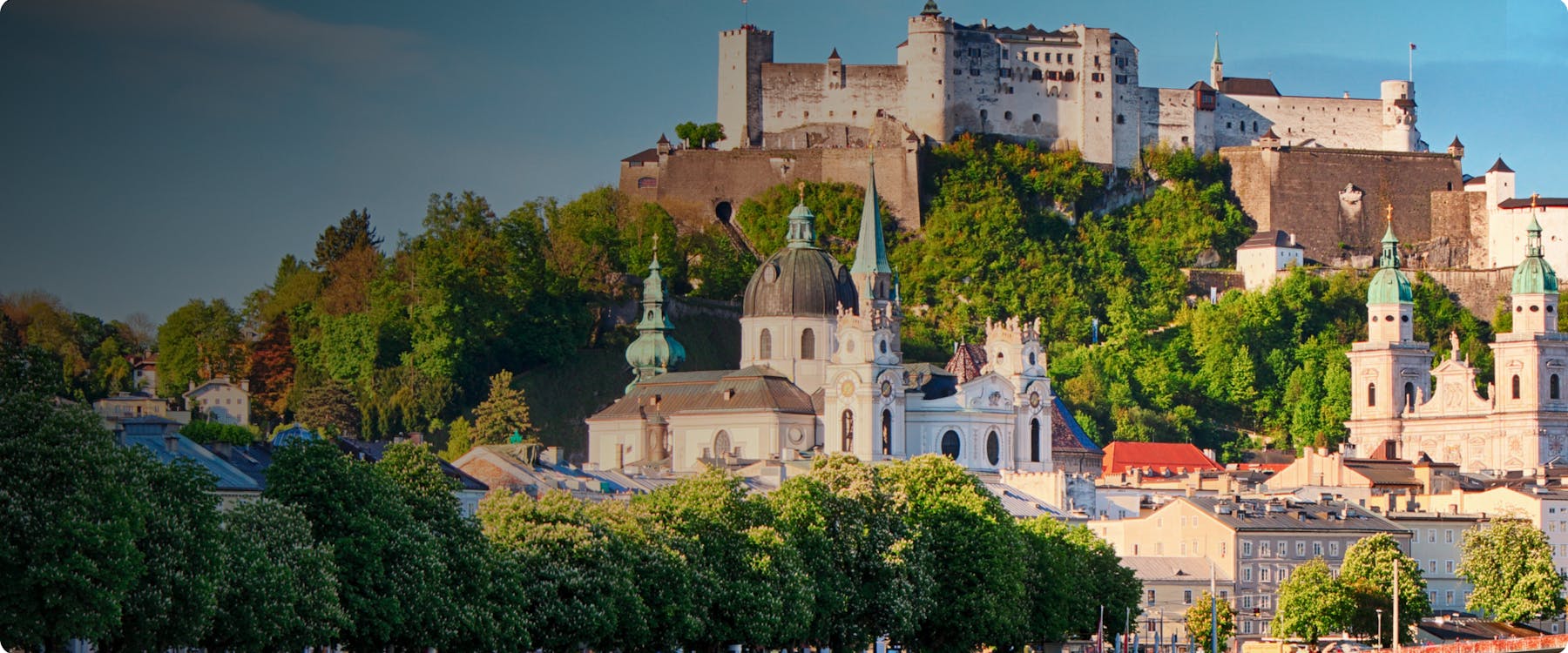 Hohensalzburg Fortress overlooking Salzburg's historic buildings and lush greenery.