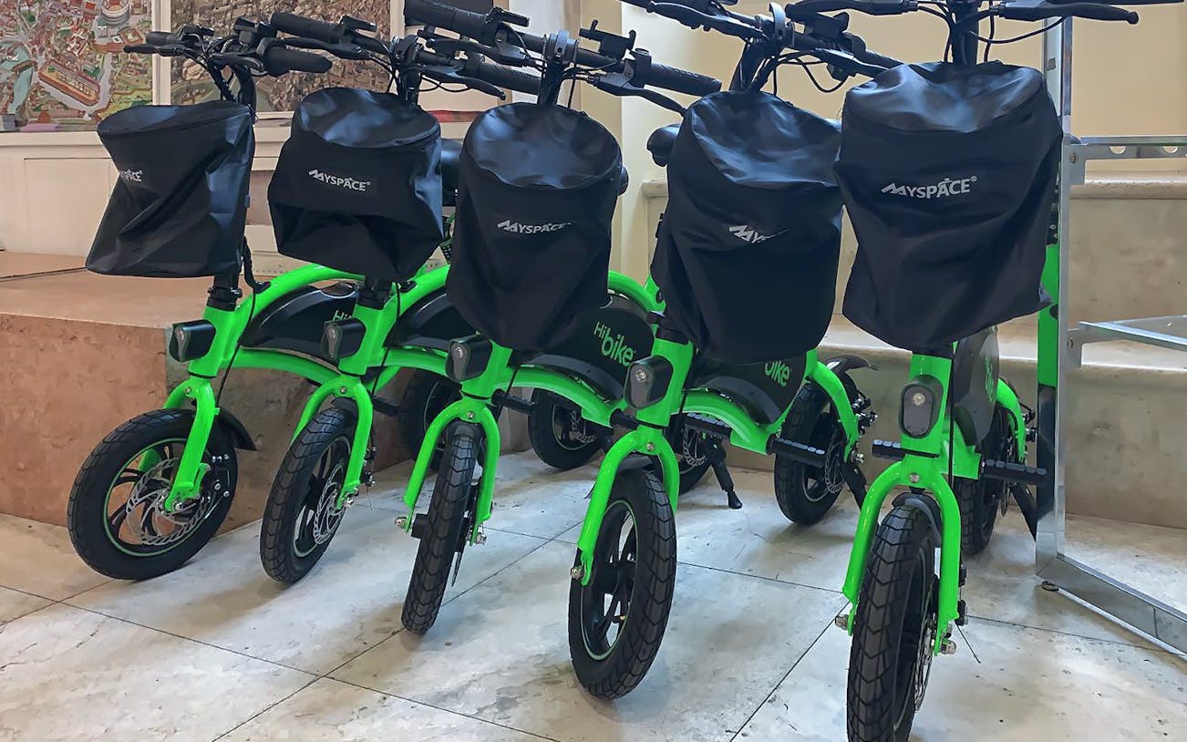 Green e-bikes lined up for Castel Sant'Angelo tour with audio guide in Rome.