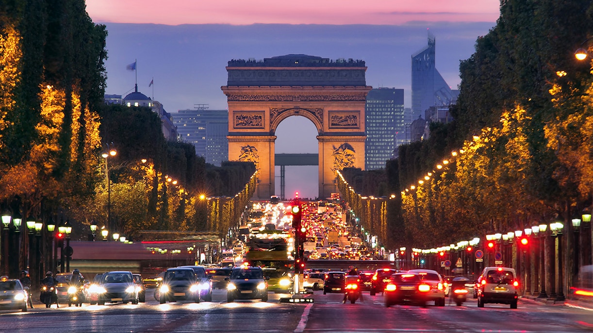 Arc de Triomphe at dusk with traffic on Champs-Élysées, Paris.