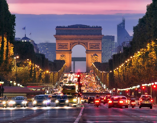Arc de Triomphe at dusk with traffic on Champs-Élysées, Paris.