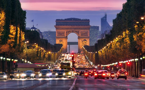 Arc de Triomphe at dusk with traffic on Champs-Élysées, Paris.