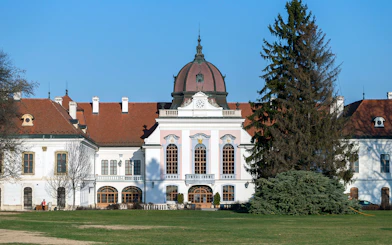Royal Palace of Godollo facade with clock tower and gardens in Hungary.
