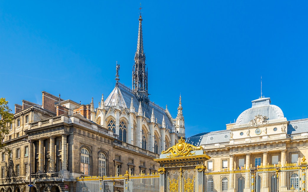 Sainte Chapelle spire and Conciergerie facade in Paris with ornate golden gate.