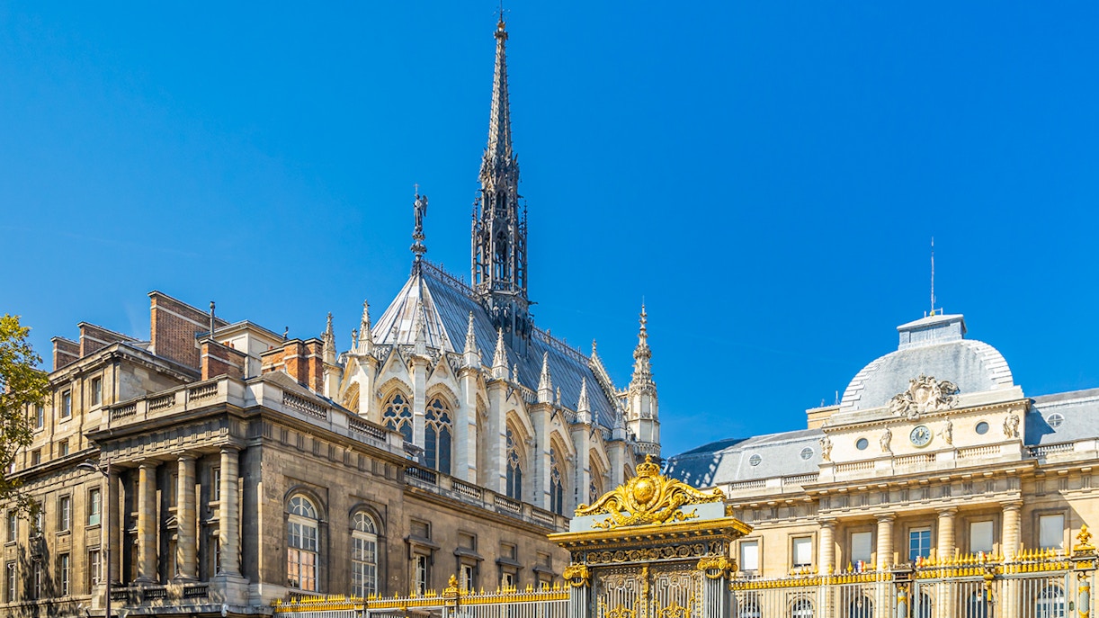 Sainte Chapelle spire and Conciergerie facade in Paris with ornate golden gate.