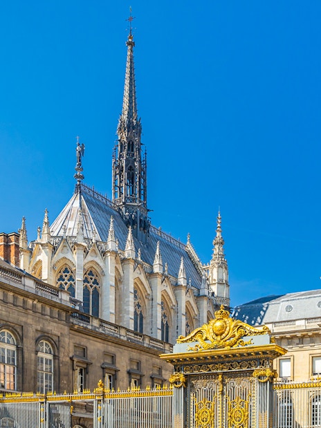 Sainte Chapelle spire and Conciergerie facade in Paris with ornate golden gate.