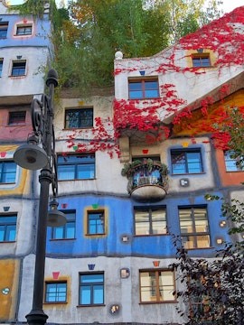Colorful facade of Hundertwasserhaus in Vienna, Austria, with vibrant red vines and unique window designs.