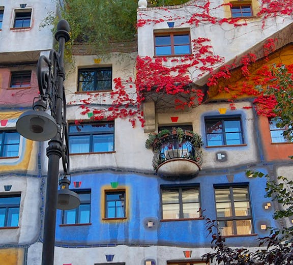 Colorful facade of Hundertwasserhaus in Vienna, Austria, with vibrant red vines and unique window designs.