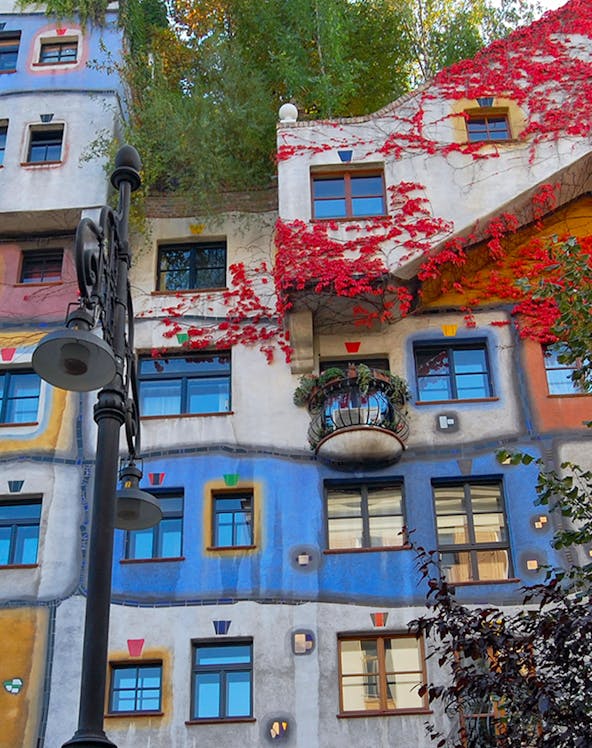 Colorful facade of Hundertwasserhaus in Vienna, Austria, with vibrant red vines and unique window designs.