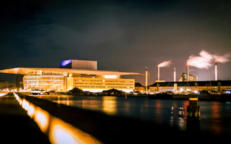 Copenhagen Opera House illuminated at night, viewed from across the water.