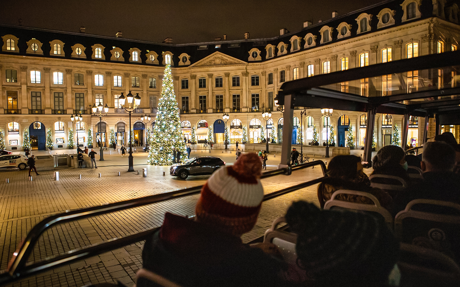 Tourists on a bus tour view Christmas lights at Place Vendôme, Paris.