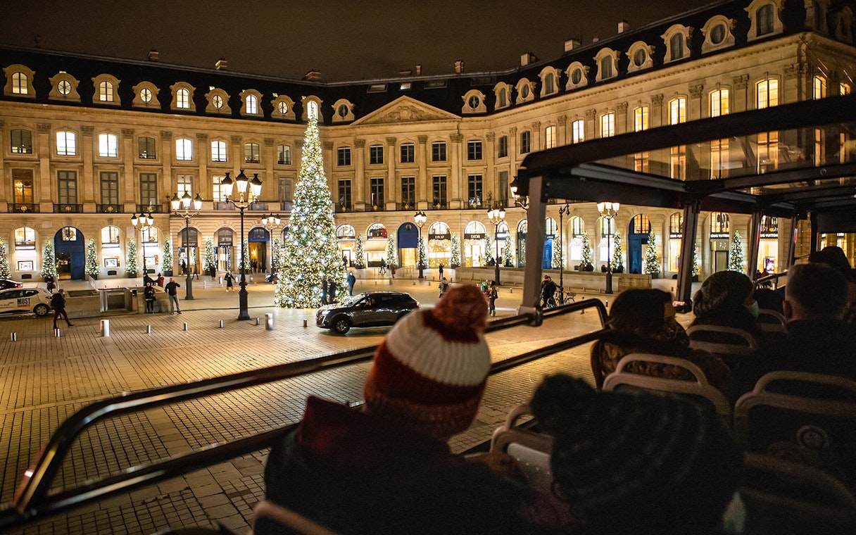 Tourists on a bus tour view Christmas lights at Place Vendôme, Paris.
