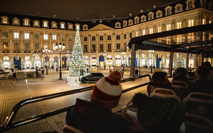 Tourists on a bus tour view Christmas lights at Place Vendôme, Paris.