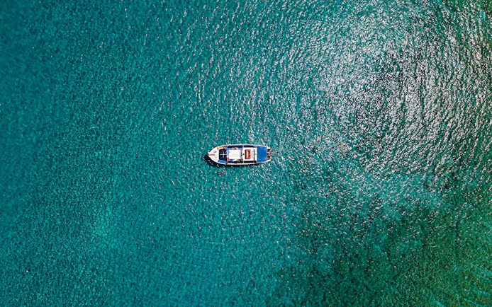 Boat cruising on turquoise sea during Lindos tour.