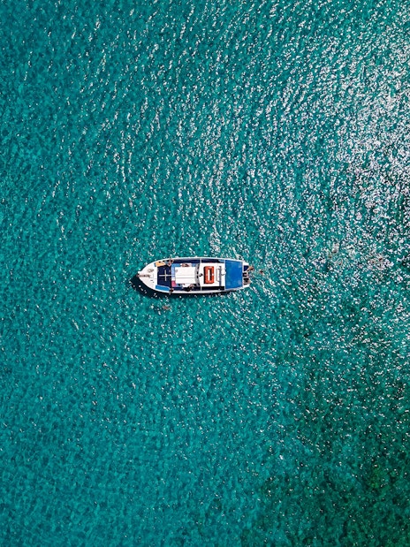Boat cruising on turquoise sea during Lindos tour.