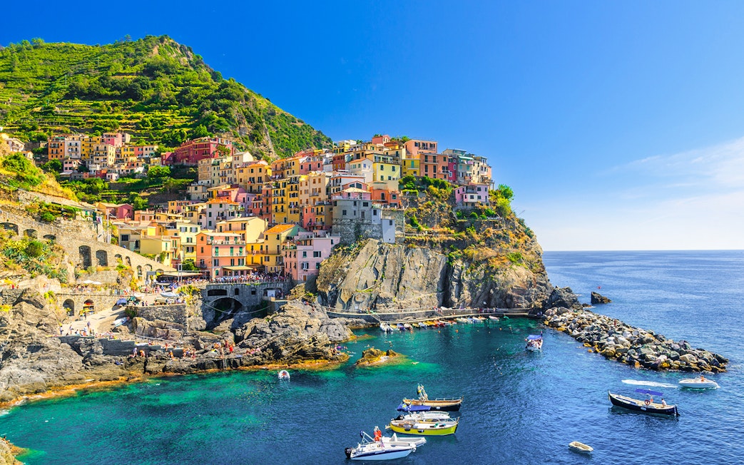 Colorful cliffside village of Manarola in Cinque Terre, Italy, with boats in the harbor.