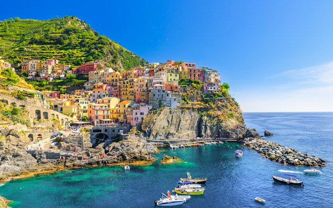 Colorful cliffside village of Manarola in Cinque Terre, Italy, with boats in the harbor.